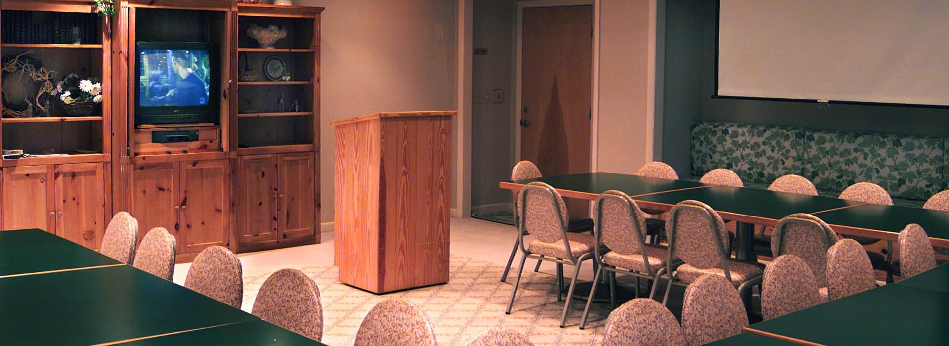 A conference room with a podium, chairs, and a television in the background.