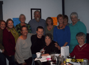 A group of twelve people posing together at a restaurant gathering.