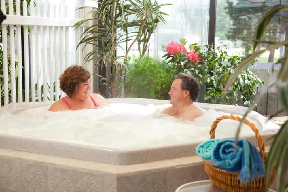 A couple enjoys a relaxing moment together in a bubbling hot tub surrounded by greenery.