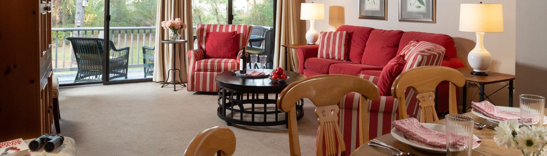 Cozy living room featuring striped furniture, a coffee table, and a dining area with a view of the outdoors.