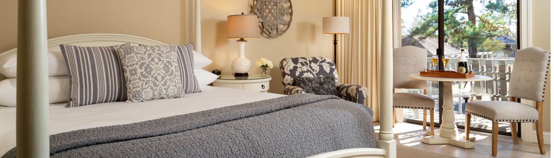 A cozy and elegantly furnished bedroom with a bed, seating area, and balcony access.