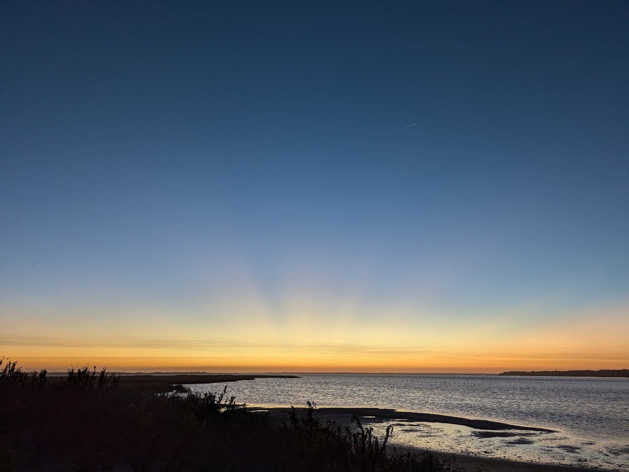 A serene sunset casts rays of light over a calm sea.